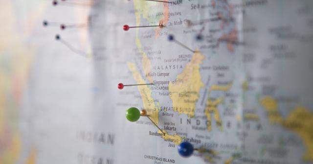 Map of the world A paper map of the world is hanging on the wall, and the image is focused in on Malaysia and Indonesia, with other areas out of focus. Pins have been stuck into the map to highlight arbitrary locations.